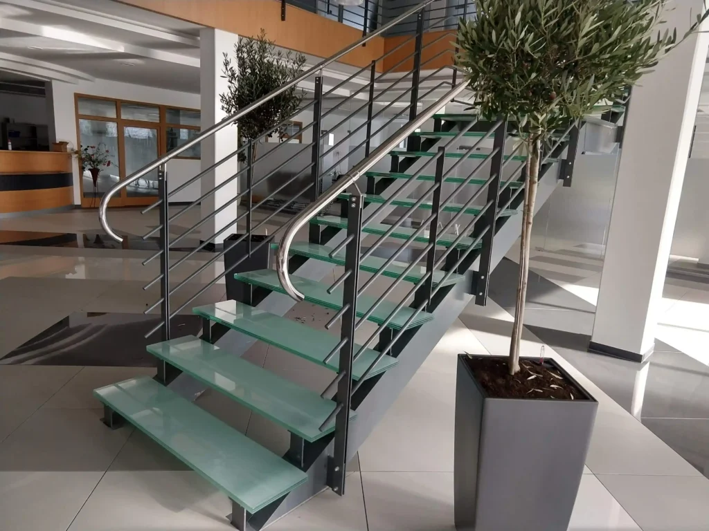 Moderné interiérové schodisko s nášľapmi z vrstveného pochôdzneho skla a nerezovým zábradlím.