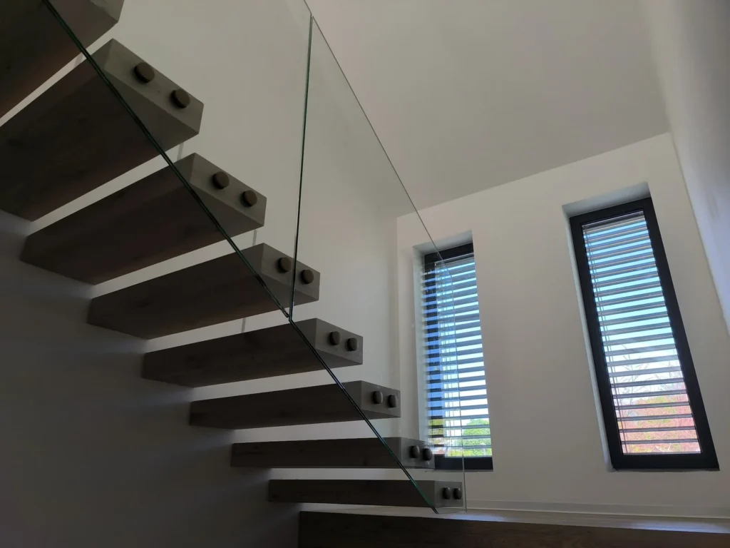 sklenené zábradlie na drevené schodisko s tmavými stupňami a minimalistickým dizajnom