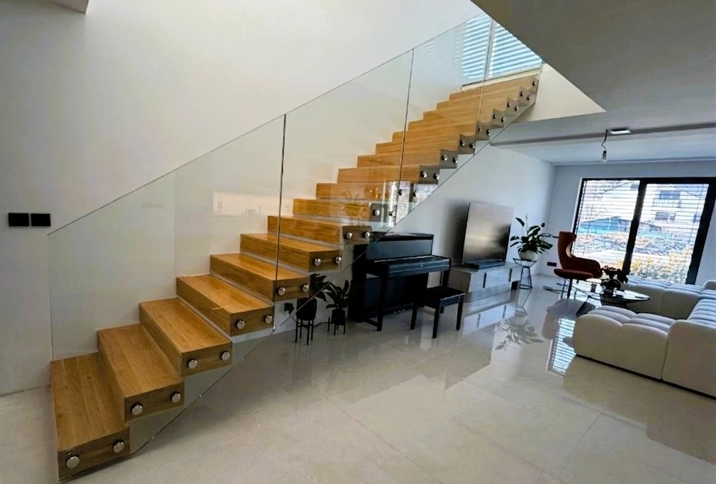 Moderné drevené schodisko so skleneným zábradlím v minimalistickej obývačke